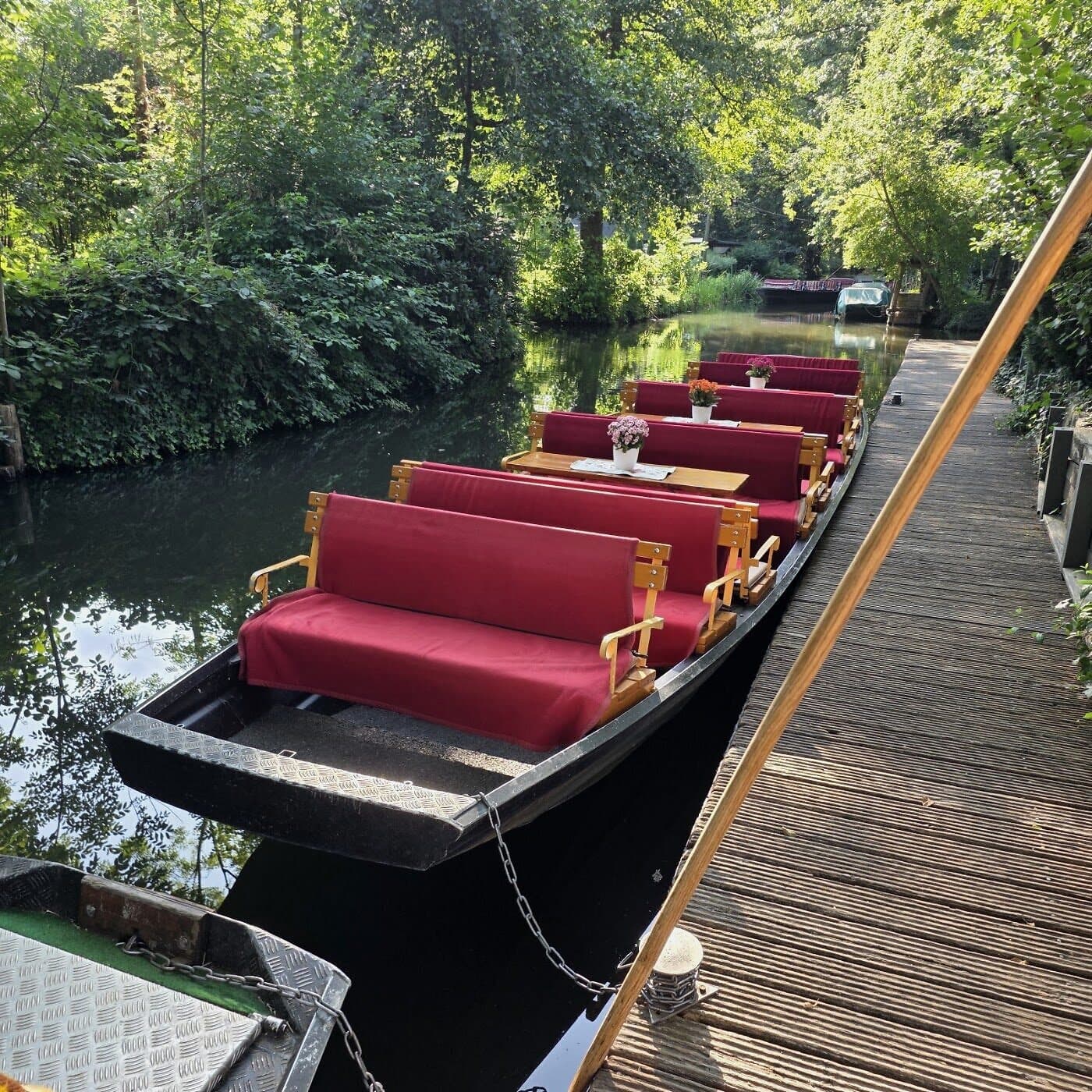 Romantische Pärchenfahrt im Spreewald: samtroter Spreewaldkahn mit Bänken am Steg für eine private Fahrt zu zweit